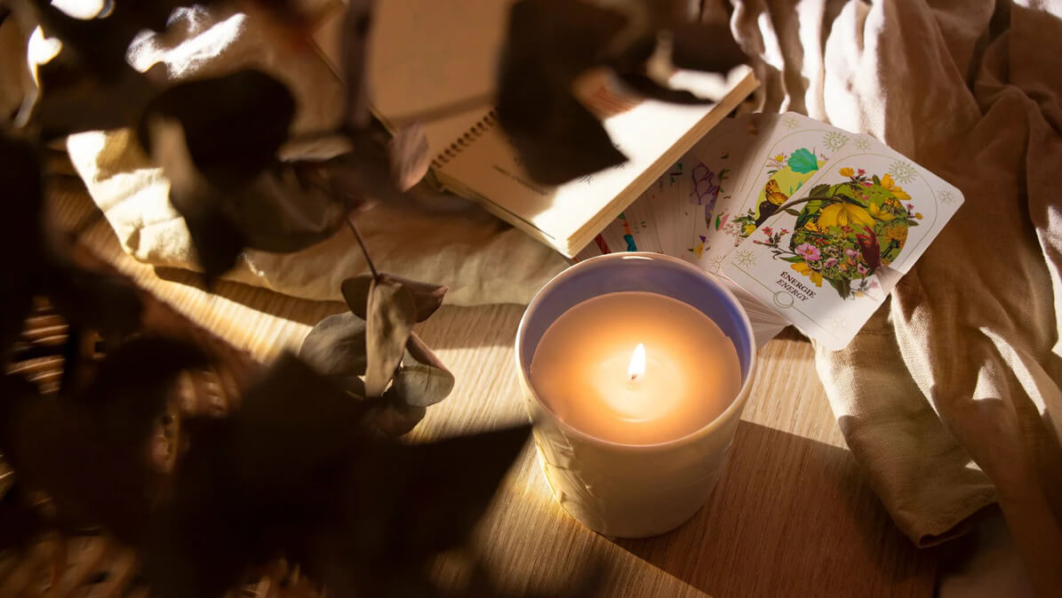 Une bougie et cahier et les carte de L'oracle du Jardin Retrouvé sur une table