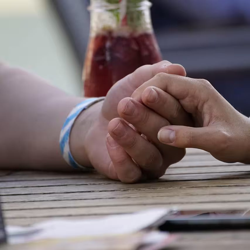 A man and a woman holding hands outside on a table in a bar