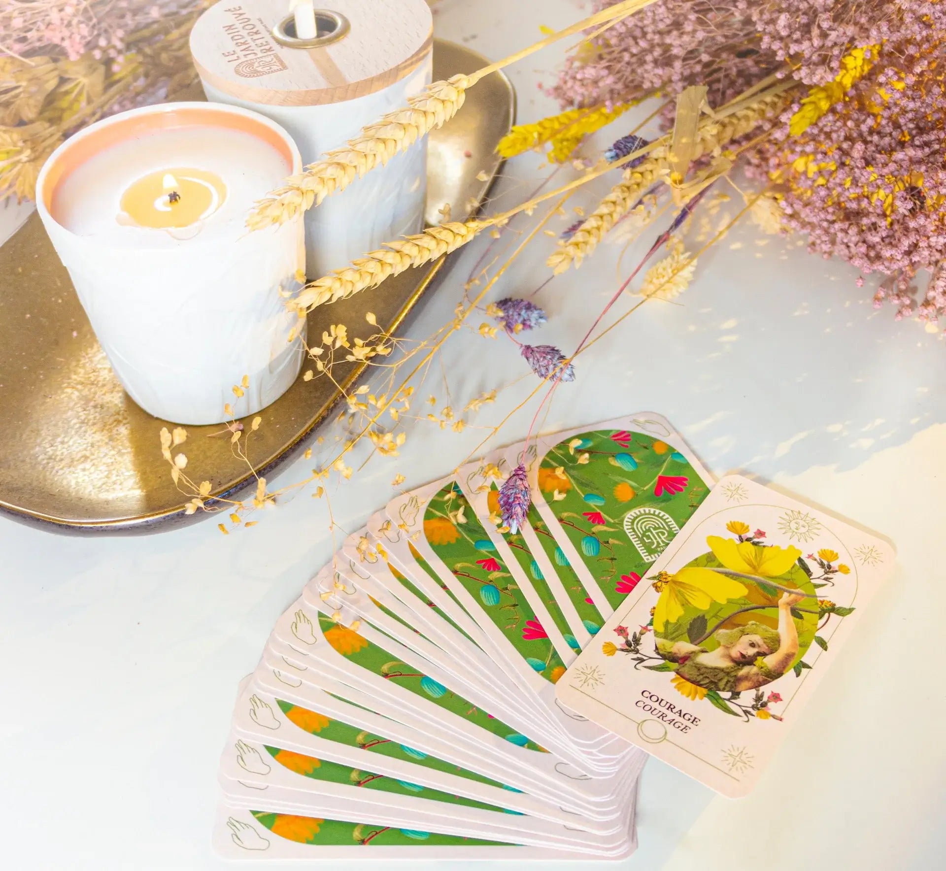 Well-being products and Oracle cards from Le Jardin Retrouvé displayed on a rustic table with flowers and wheat, celebrating inner serenity.